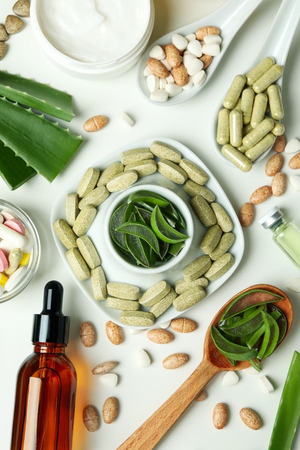 Glass vials and a green leaf on a white surface, representing cellular wellness.